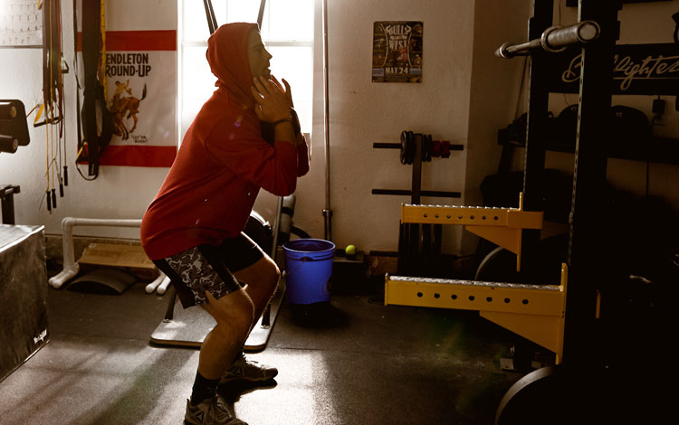 Photo of a man squatting weights in a gym.